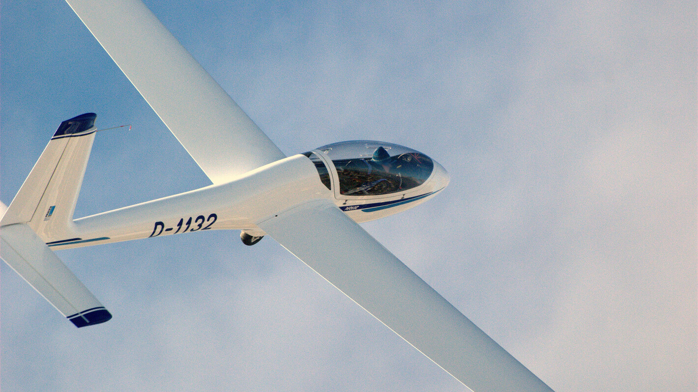 SZD-54-2 Perkoz Segelflugzeug im Flug vor leicht bewölktem Himmel.